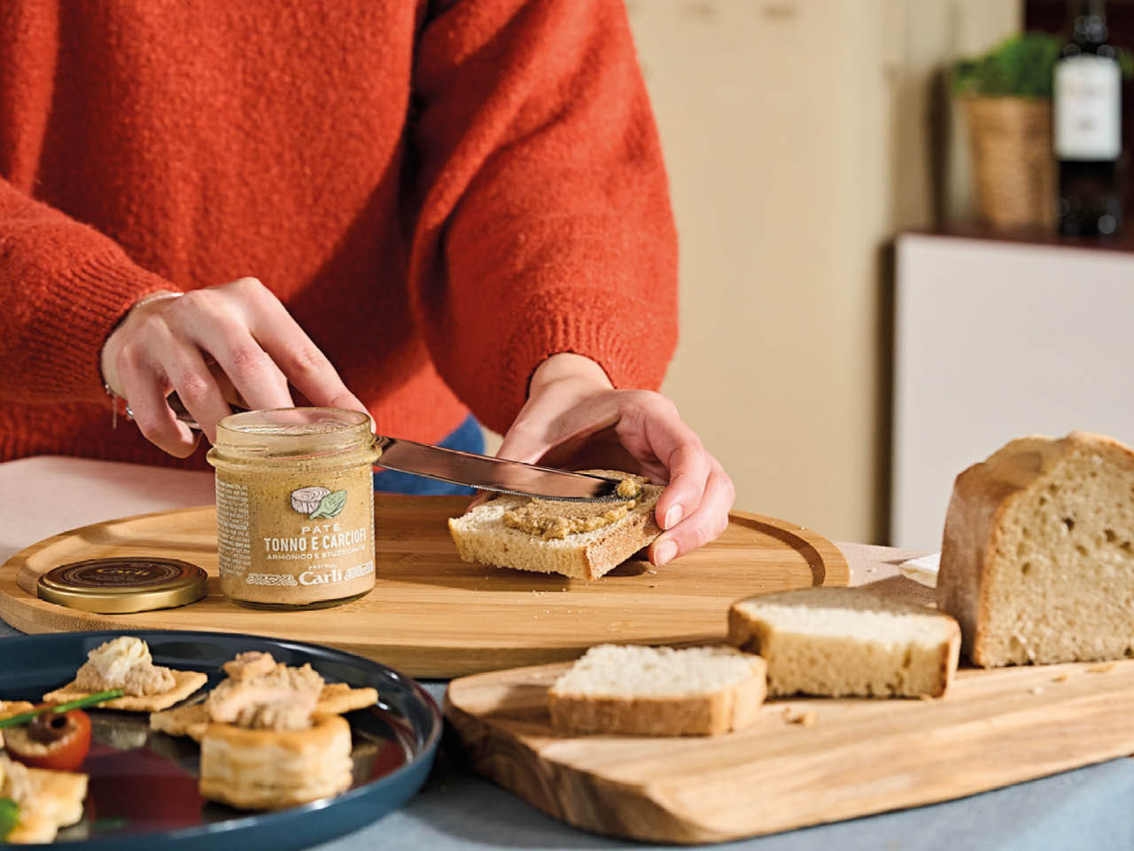 main qui prepare une tartine avec creme artichauts et thon